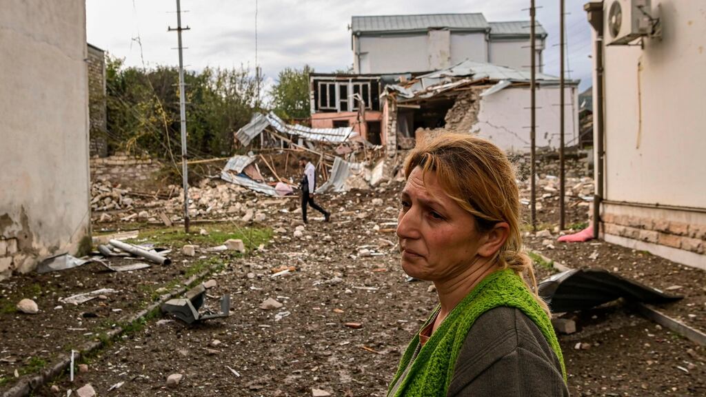 A woman stands in front of a destroyed house  in the Nagorno-Karabakh region’s main city of Stepanakert on Thursday, during the ongoing fighting between Armenia and Azerbaijan over the disputed region. Photograph: Aris Messinis/AFP via Getty Images