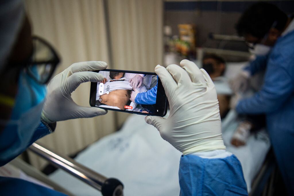 A doctor checks on a patient with sores caused by a monkeypox infection while another takes a picture, in the isolation area for monkeypox patients at the Arzobispo Loayza hospital, in Lima. Photograph: Ernesto Benavides /AFP via Getty Images
