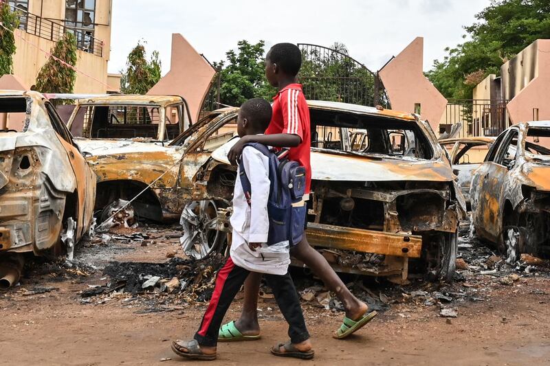 Children walk past burned cars outside the headquarters of president Bazoum's Nigerien Party for Democracy and Socialism in Niamey. Photograph: AFP/Getty Images