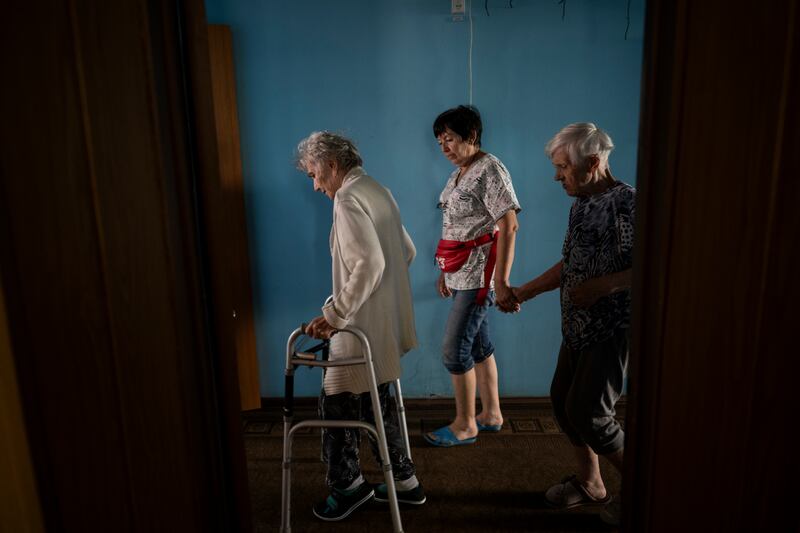Tamara Bohun (82), and Valentina Karilidze (89), patients who have dementia, are escorted by caregiver Natalya Savelyeva at the St. Natalia nursing home in Zaporizhzhia. Photograph: Lynsey Addario/New York Times