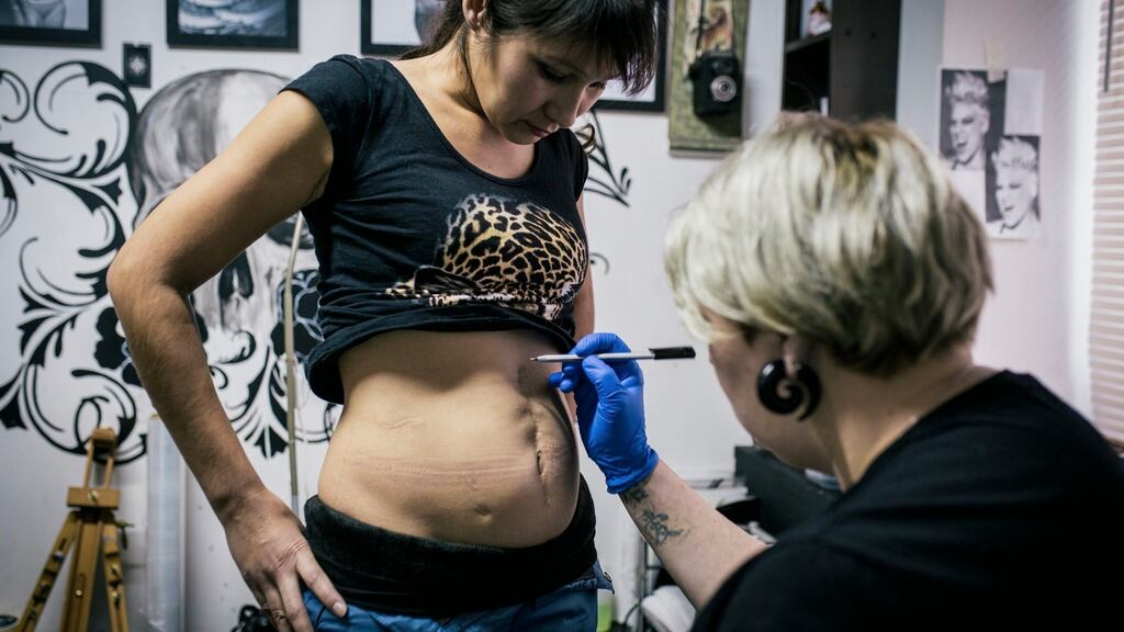 Tattoo artist Yevgeniya Zakhar works on a tattoo for Lyaysan, a victim of domestic violence, in Ufa, Russia. Photograph: Vadim Braydov/AP