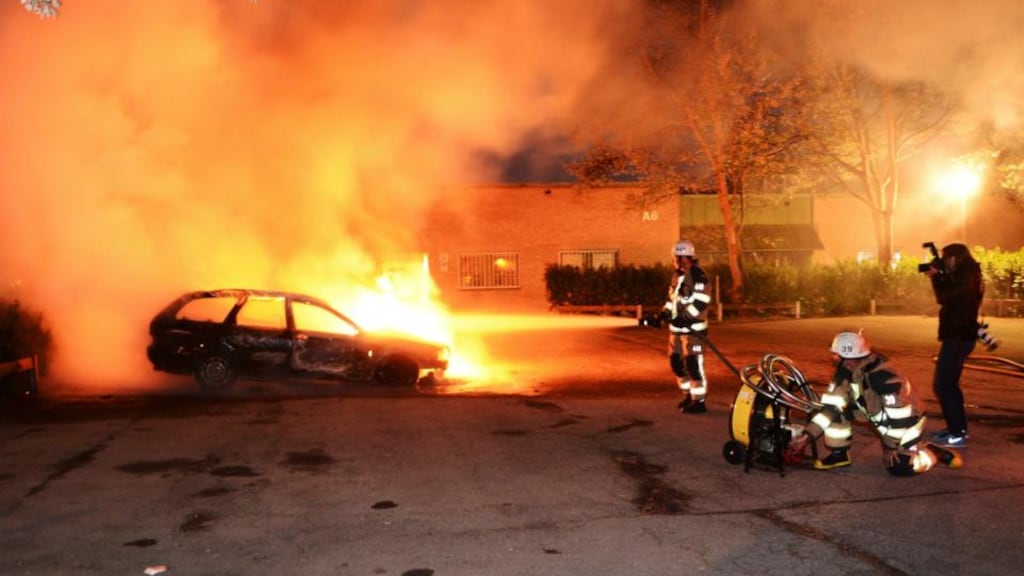 Firefighters extinguish a burning car, following riots in the Stockholm suburb of Kista. Photograph: Reuters