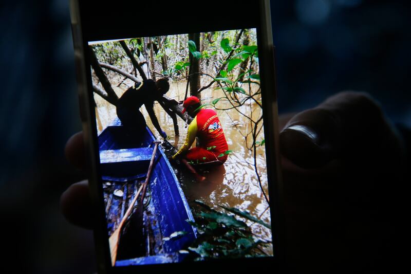 A firefighter holds a phone with a picture showing the moment when a backpack was found during a search for Indigenous expert Bruno Pereira and freelance British journalist Dom Phillips in Atalaia do Norte