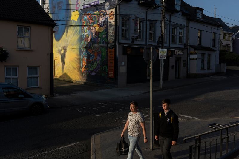 Artem Baranovskyi walking with his son to school near a pro-Ukrainian mural in Letterkenny. Baranovskyi is working two jobs in the town. Photograph: Paulo Nunes dos Santos/New York Times
