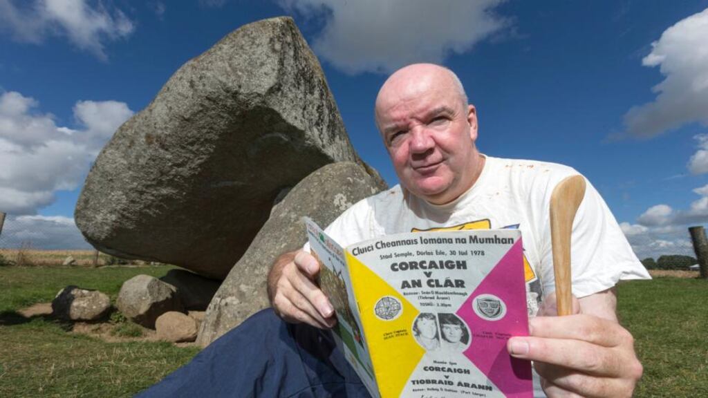 Clare hurling fan Leo McGough pictured near his home in Carlow at the Brownshill Dolmen. Leo is holding a match programme from the Cork-Clare match in 1978, his lucky hurley and a t-shirt from the 1995 Clare All-Ireland homecoming. Photograph:  Dylan Vaughan.
