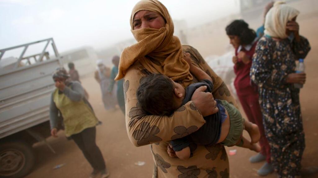 A Kurdish Syrian refugee waits for transport during a sand storm on the Turkish-Syrian border yesterday. Photograph: Murad Sezer/Reuters