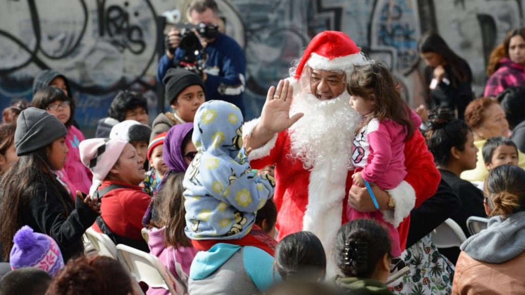 A man dressed as Santa Claus greets children and families waiting for holiday gifts and toys to be distributed to underprivileged children at the Fred Jordan Mission in Los Angeles. Photograph: Phil McCarten/Reuters