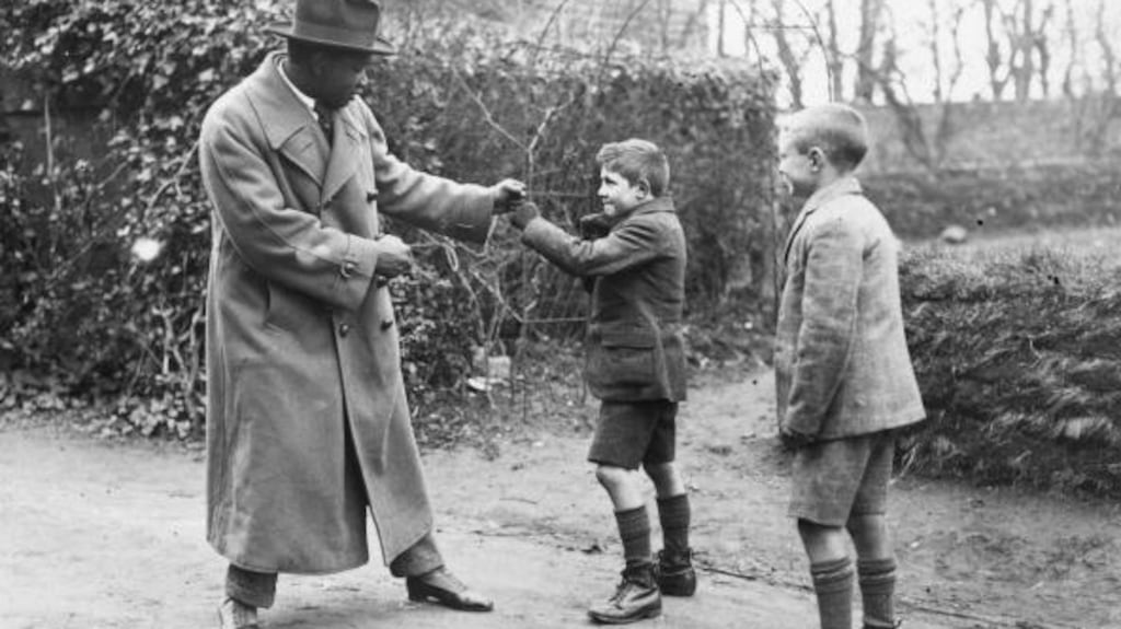 Senegalese light-heavyweight world champion boxer Battlin’ Siki (Louis Phail) mock-boxing with two boys in Dublin. (Photo by Walshe/Getty Images)