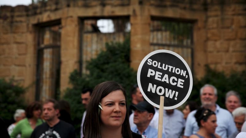 A woman holds a placard during a demonstration in favour of a peace settlement on divided Cyprus, outside a venue where leaders of estranged Greek and Turkish Cypriots met, in NicosiPhotograph: Yiannis Kourtoglou/Reuters
