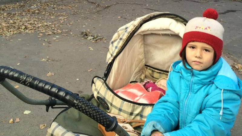Sasha (5) with sister Ella (1) outside a ruined school next to the unlit, unheated bomb shelter where they spend nights with their mother and more than a dozen other people. Photograph: Daniel McLaughlin