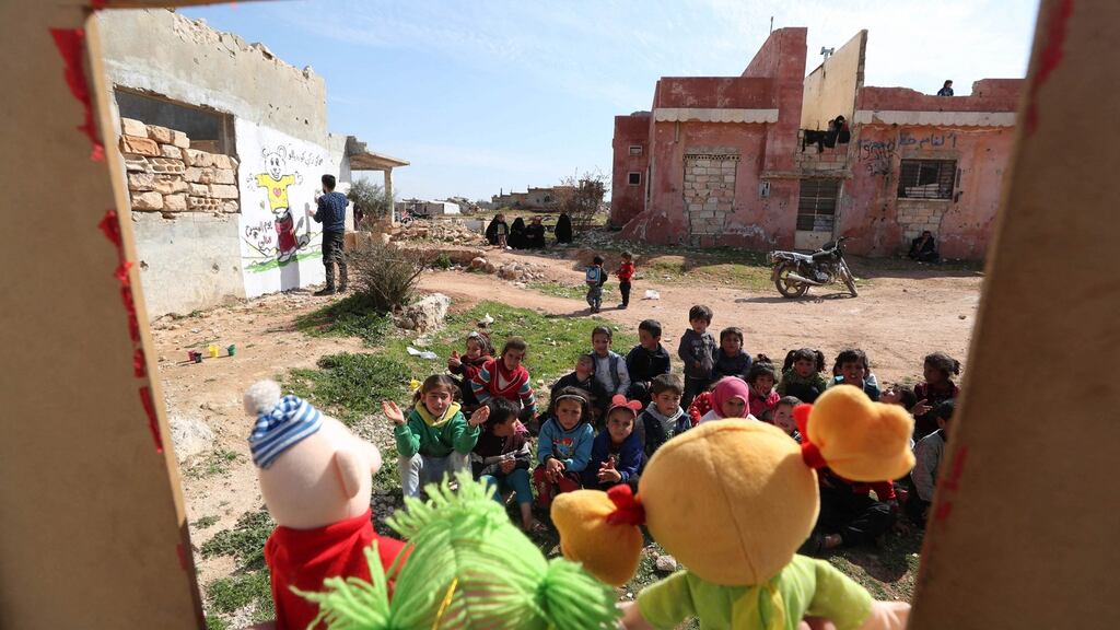 Syrian children watch a puppet show performed by a local theatre group amidst the ruins of buildings destroyed during Syria’s civil war, in al-Fua, in the country’s northwestern Idlib province. Photograph: Omar Haj Kadour/AFP/Getty