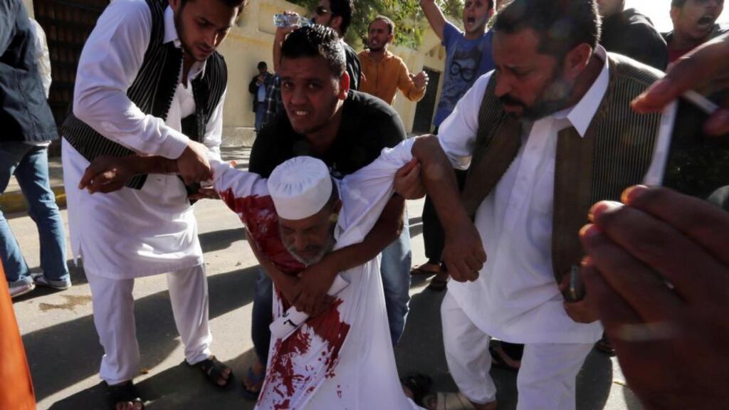 People carry a man who was injured when Libyan militiamen opened fire into a crowd of protesters in Tripoli today. Photograph: Reuters