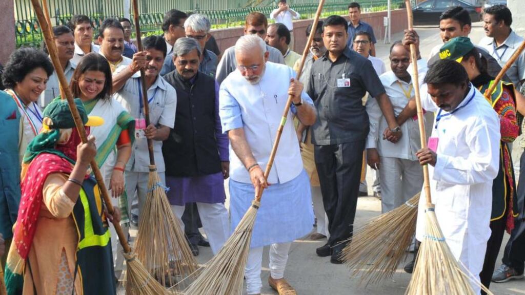 India’s prime minister Narendra Modi (centre) helps to clean a road in New Delhi yesterday as part of his campaign campaign to promote cleanliness and better sanitation in the country. Photograph: EPA/Indian Press Information Bureau