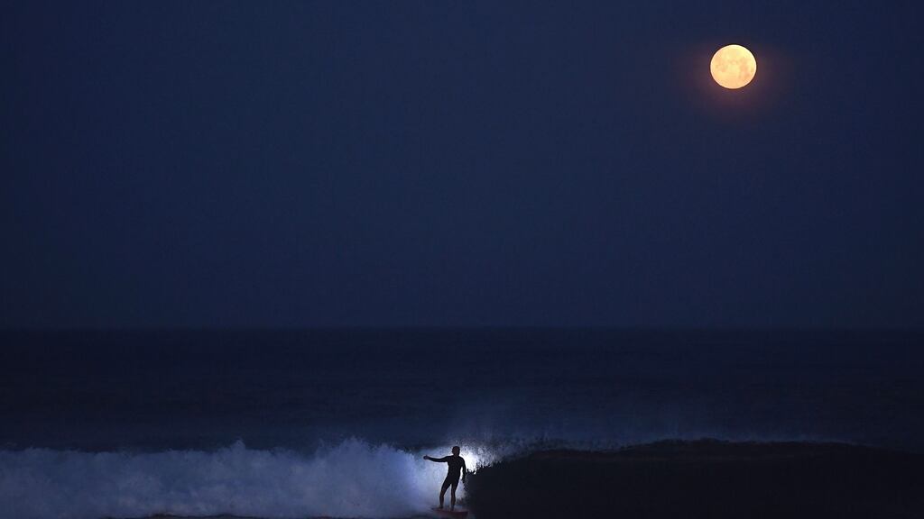 Helmut Igel surfs under a full moon near San Diego in California. Photograph:Donald Miralle/The New York Times