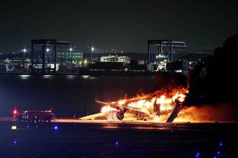 Evacuation slides were deployed before fire engulfed the plane. Photograph: JIJI Press/AFP/Getty Images