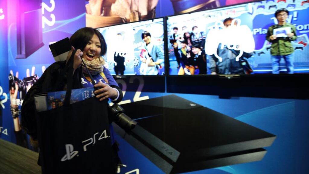 A customer holds a bag containing the Sony Computer PlayStation 4 (PS4) video game console after purchasing at the Sony showroom in Tokyo. Photograph: Tomohiro Ohsumi/Bloomberg