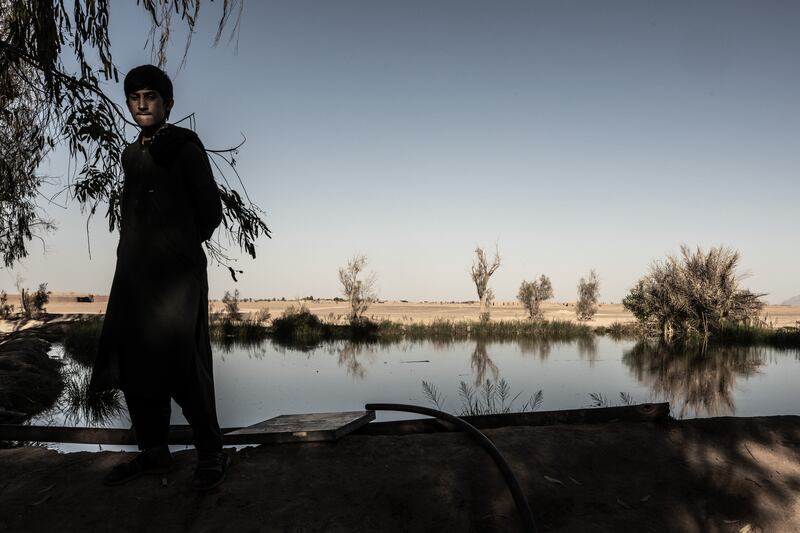A young man standing near a private reservoir, fed by water pumped by solar power, with dry fields surrounding it, in southwest Afghanistan’s arid Bakwa district on April 22nd, 2023. Photograph: Bryan Denton/The New York Times