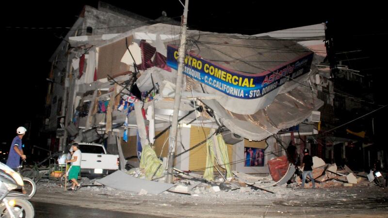 People walk near a damaged house after an earthquake struck off the Pacific coast in Manta, Ecuador on Saturday. Photograph: Reuters
