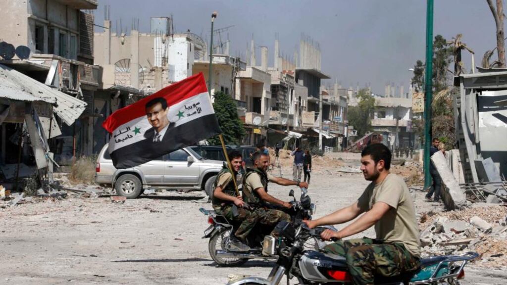 Forces loyal to Syria’s president Bashar al-Assad carry the national flag as they ride on motorcycles in Qusair. Photograph:  Mohammed Azakir/Reuters