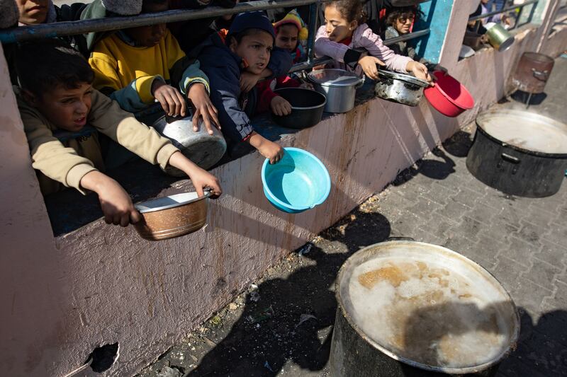 Displaced Palestinians hold empty pots and buckets as they line up to receive food aid provided by a Palestinian youth group, at Rafah refugee camp, southern Gaza Strip. Photograph: Haitham Imad/Shutterstock