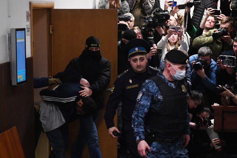 A suspect in the attack on Crocus City Hall in Moscow is escorted by Russian law enforcement officers to his pre-trial detention hearing at  Basmanny District Court in Moscow on Sunday. Photograph: Olga Maltseva/AFP/Getty