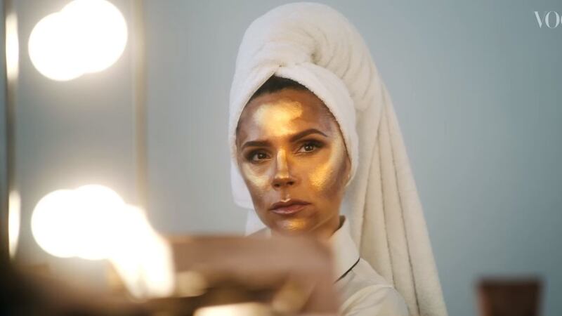 Victoria Beckham glittering in gold face in a scene from the video. Photograph: Vogue/YouTube