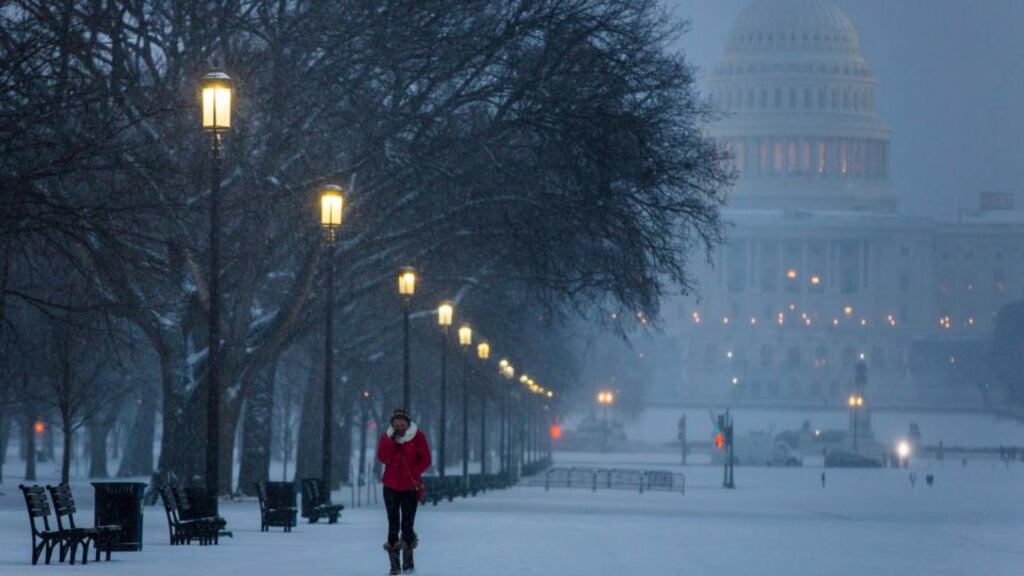 A visitor to the National Mall walks through a late afternoon snowfall in Washington yesterday. Photograph: EPA