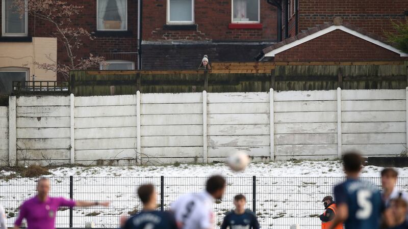 A spectator watches the game from behind a fence. Photo: Martin Rickett/PA Wire