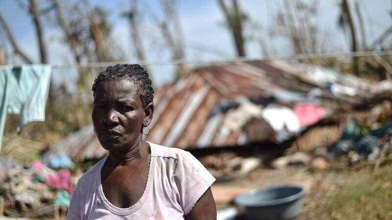 A Haitian woman stands in front of the remains of her house where she and her husband became trapped during Hurricane Matthew. Photograph: Hector Retamal/AFP/Getty Images