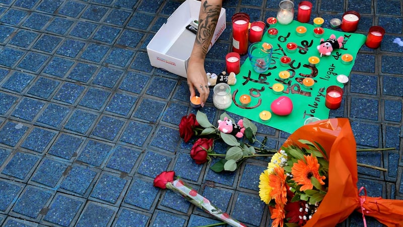 A woman places a candle next to flowers and a message to the victims on August 18th. Photograph: Javier Soriano/AFP/Getty Images