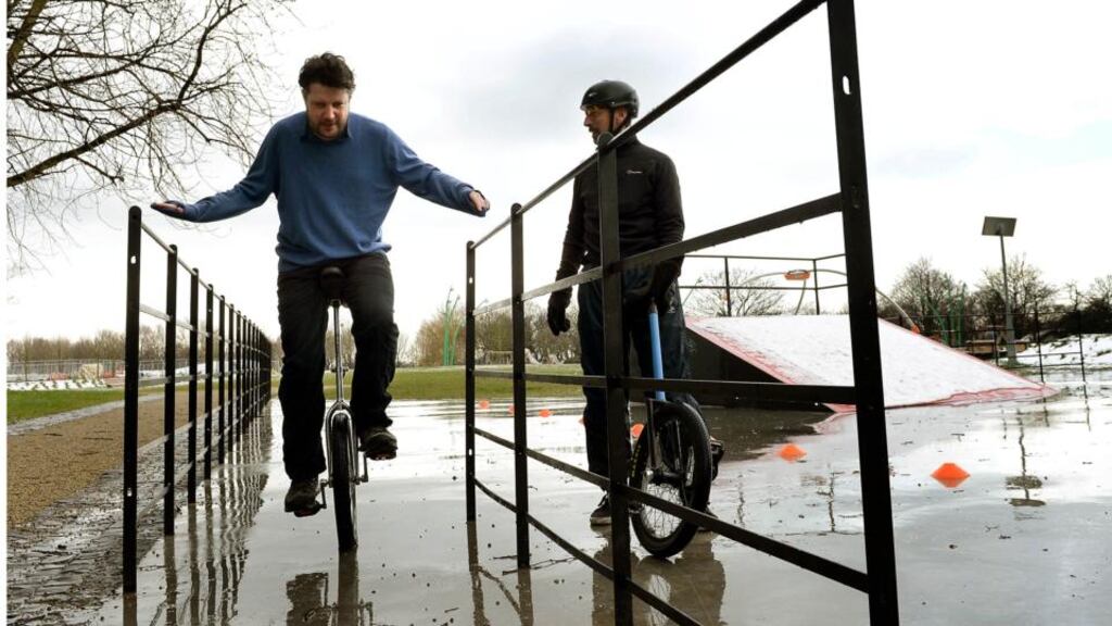 Patrick Freyne learning to unicycle under the watchful eye of Anthony Furlong in Fairview Park, Dublin. Photograph: Brenda Fitzsimons