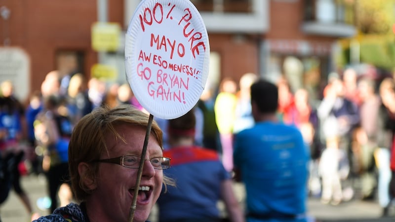 A spectator shouts her encouragement as runners make their way through Chapelizod. Photograph: David Fitzgerald/Sportsfile