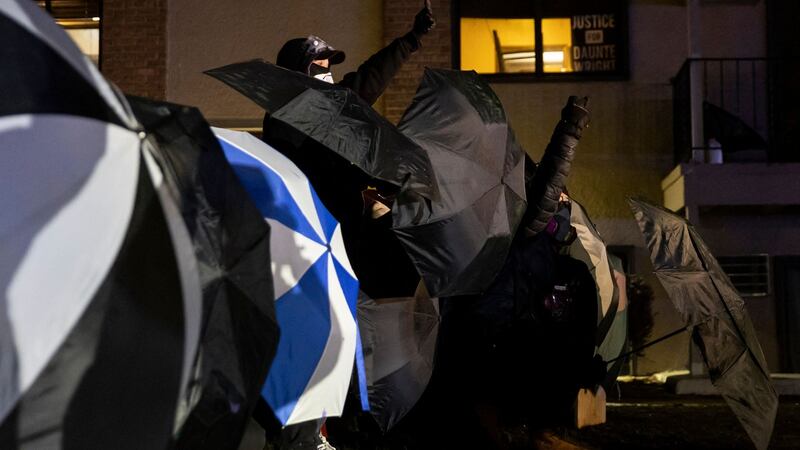 Protesters protect themselves with umbrellas against tear gas and pepper balls outside the Brooklyn Center police station during a semonstration on Tuesday. Photograph: Getty Images