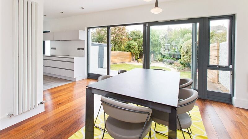 The rear reception room and original small kitchen were knocked through to create an open-plan kitchen and dining area that run across the rear with custom-designed floor to ceiling glazed doors opening to the garden