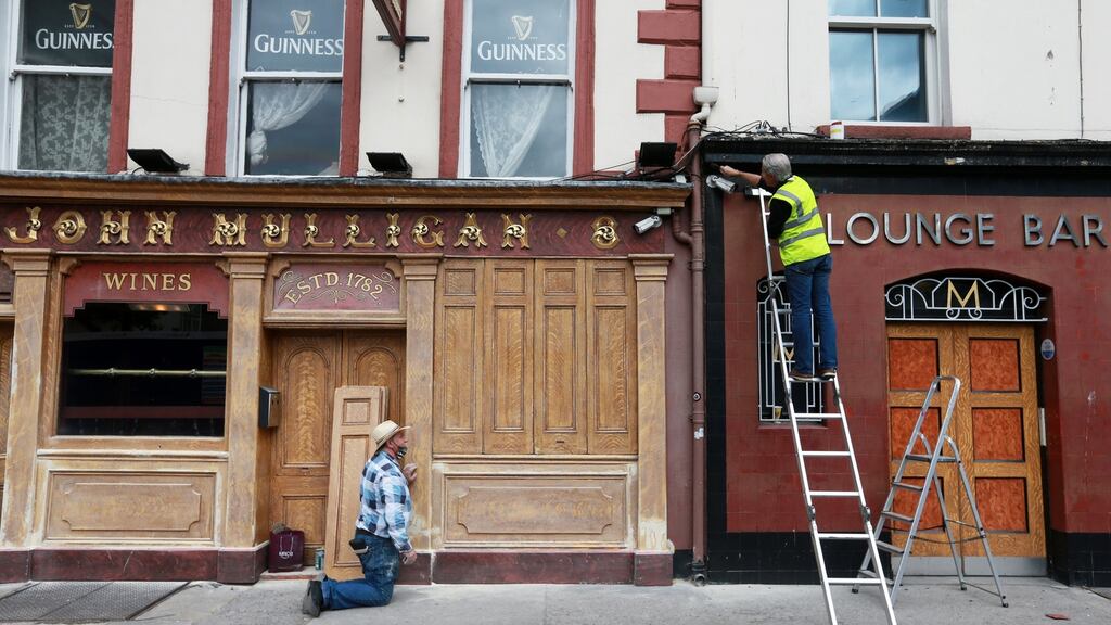 Artists Richard Levins (left) and Paul Cooke begin work on the exterior of Mulligans pub on Poolbeg Street which, like all other pubs that don’t serve food, has to remain closed now until August 10th. Photograph : Laura Hutton / The Irish Times