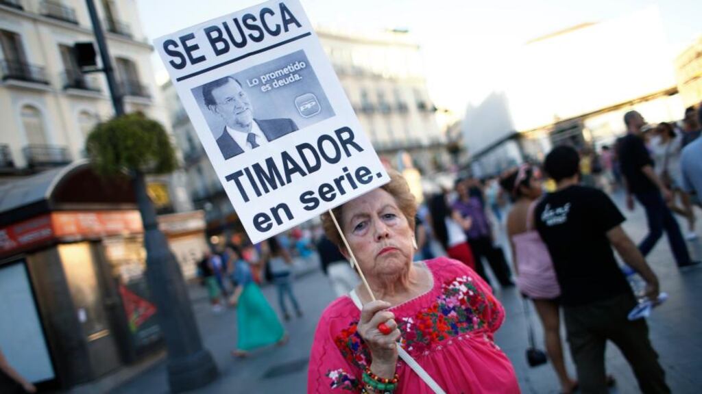 A woman holds a placard depicting Mariano Rajoy that reads “Wanted, serious con artist” during a protest calling for the Spanish prime minister to step down due to his implication in a corruption scandal, at Madrid’s landmark Puerta del Sol. Photograph: Reuters/Juan Medina