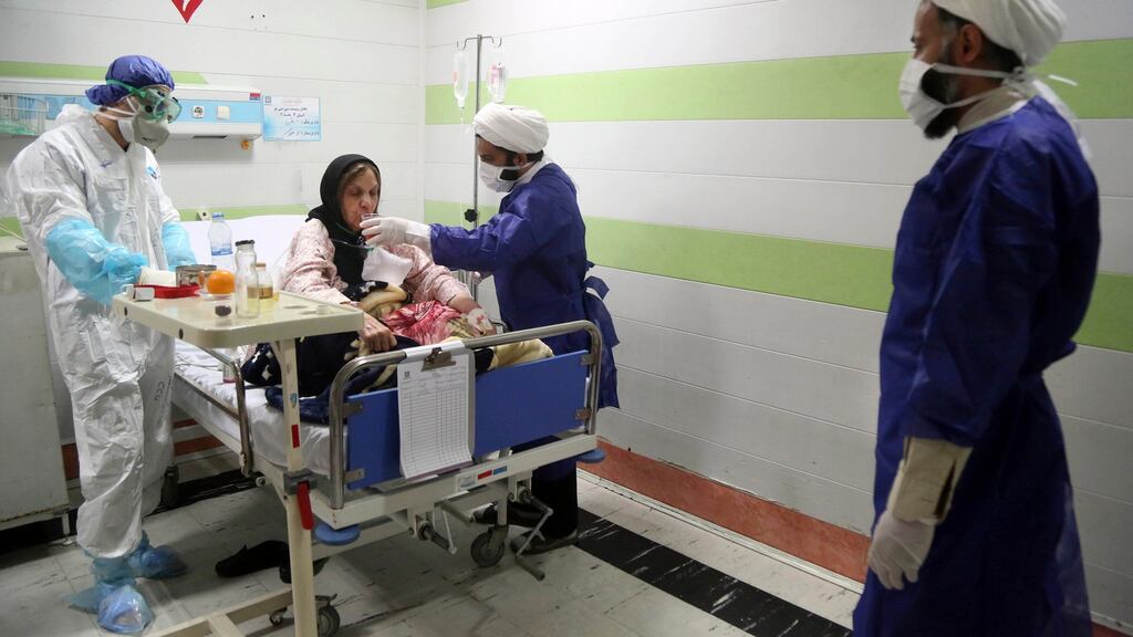 A cleric, right, assists a medic treating a patient infected with the new coronavirus, at a hospital in Qom, about 125 kilometers south of the capital Tehran, Iran. File Photograph: Mohammad Ali Marizad/Rasa News Agency via AP