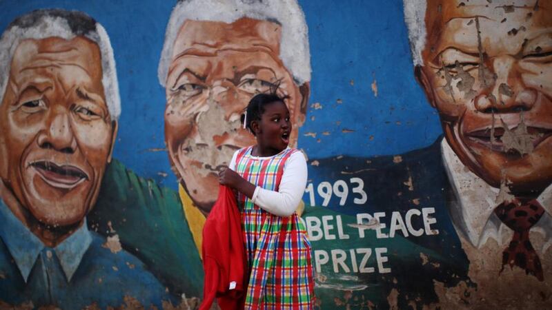 A young girl walks past a mural of Nelson Mandela near to Regina Mundi Church in the Soweto township  in Johannesberg, South Africa. Photograph:  Dan Kitwood/Getty Images