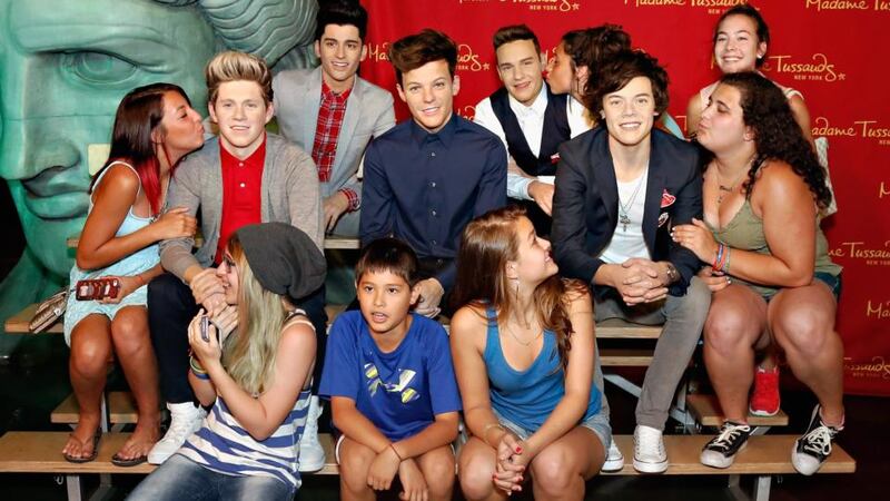 Fans pose with the wax figures of One Direction. Photograph: Getty