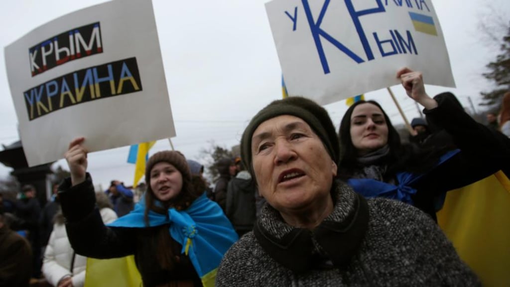 People attend a pro-Ukrainian rally in Simferopol yesterday. Ukraine’s interim leaders established a new national guard yesterday and appealed to the United States and Britain for assistance against what they called Russian aggression in Crimea under a post-Cold War treaty. The poster (left) reads: “Crimea is Ukraine”. Photograph: Reuters/David Mdzinarishvili
