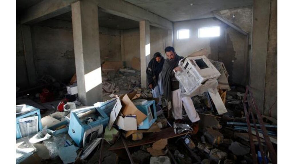 People return to collect their belongings from their shop at the site of yesterday's bomb attack. Photograph: Naseer Ahmed/Reuters