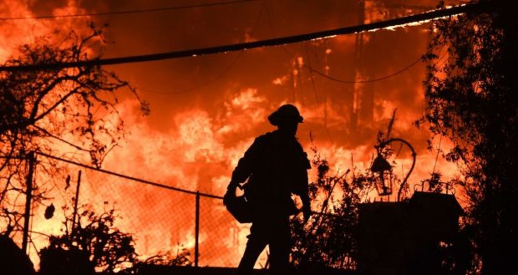 A firefighter is silhouetted by a burning home along Pacific Coast Highway during the Woolsey Fire in California in November 2018. File photograph: AFP