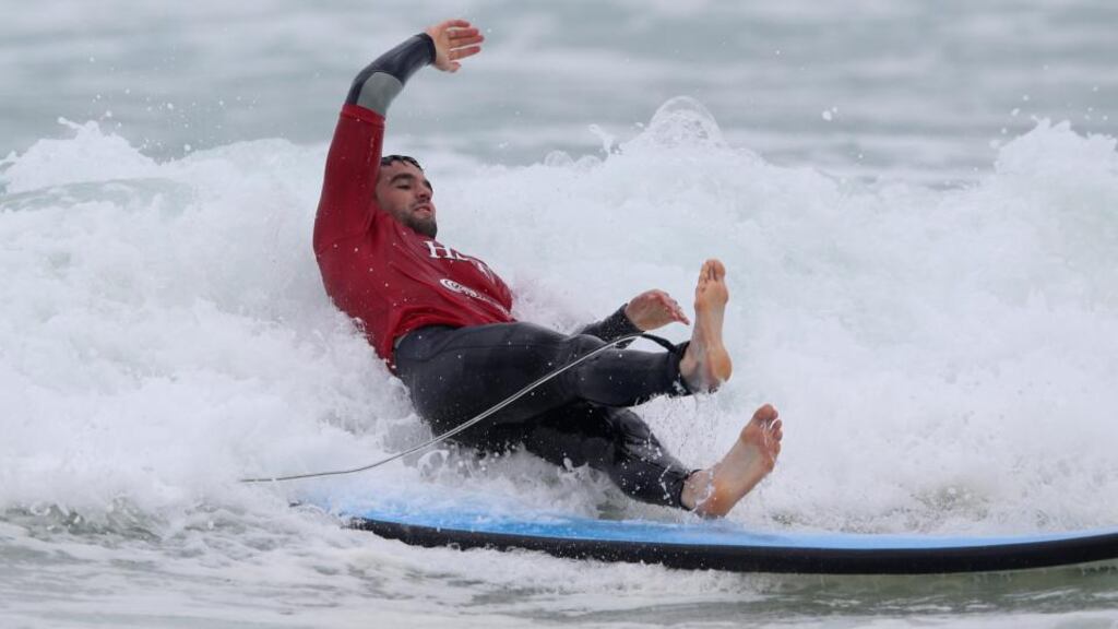 Conor Murray of the British & Irish Lions, falls off the surfboard during surfing lessons on Bondi Beach.