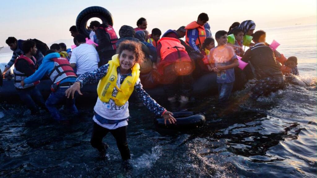 A Syrian child smiles as refugees arrive at a beach on the Greek island of Kos after crossing a part of the Aegean sea from Turkey to Greece in a dinghy. Photograph: Milos Bicanski/Getty Images