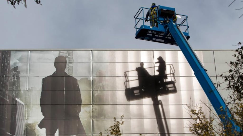 Workers install an advertisement for a new S’UHD TV from Samsung Electronics on the side of the Las Vegas Convention Center in Las Vegas.