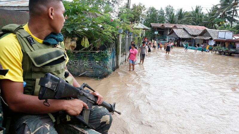 A Filipino government troop conducts patrol as villagers wade through floodwater in Salvador in the Lanao del Norte province. Photograph: Jeoffrey Maitem/EPA.