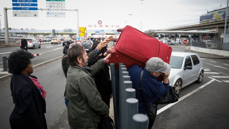 Travellers hand their luggage to friends over a fence as they walk back into Orly airport, south of Paris, when flights began to resume on Saturday. Photograph: Kamil Zihnioglu/AP