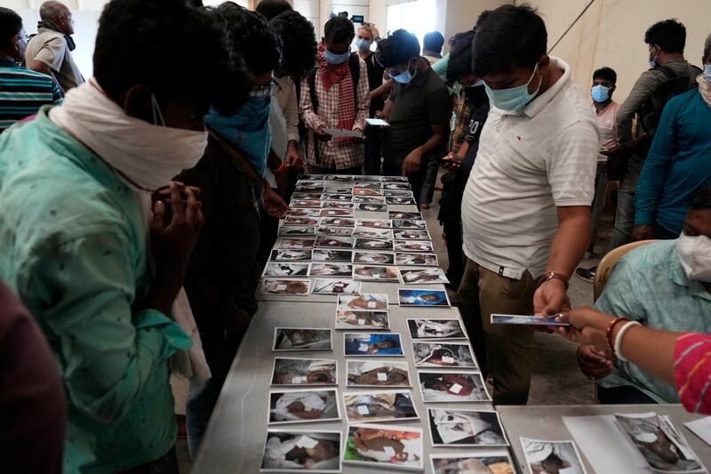 People look at photographs to identify passengers who were travelling in the derailed trains. Photograph: Rafiq Maqbool/AP