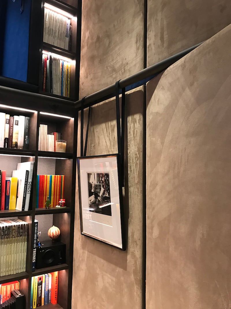 Roselind Wilson uses a leather as straps from which to suspend a framed photograph on a blackened bronze-coloured and powder-coated steel picture rail.