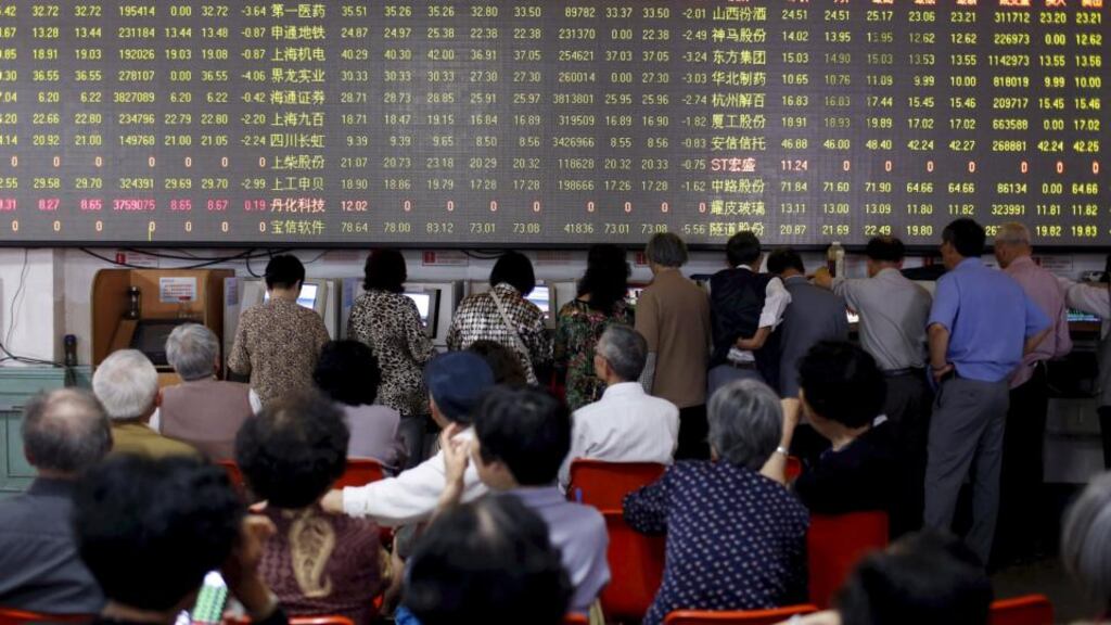 Investors look at screens showing stock information at a brokerage house in Shanghai